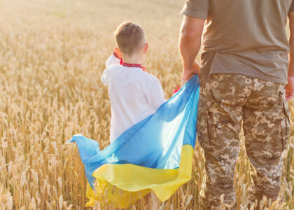 Military man, child with Ukraine flag Military man and child with Ukraine flag in wheat field. Ukraine independence day concept. Stop war in Ukraine. Save Ukraine